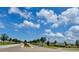 Scenic community street with trees, street lights, and view of the Belmont West entrance sign at 9520 Lemon Drop Loop, Sun City Center, FL 33573