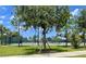 Outdoor tennis court with green surface, enclosed by a fence and shaded by trees at 9520 Lemon Drop Loop, Sun City Center, FL 33573