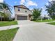 A two-story home featuring a long driveway leading to a gray garage door and landscaping at 9605 Channing Hill Dr, Sun City Center, FL 33573