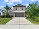 Charming two-story home with a gray garage door, a well-manicured lawn, and landscaped garden beds at 9605 Channing Hill Dr, Sun City Center, FL 33573
