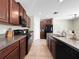 Galley kitchen featuring dark wood cabinetry, tile flooring, granite countertops and stainless steel appliances at 9605 Channing Hill Dr, Sun City Center, FL 33573