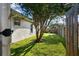 Backyard view showing the side of the house and green grass with a border fence and lush foliage at 10516 Gretna Green Dr, Tampa, FL 33626