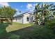 Backyard view showing the side of the house, green grass, and tropical landscaping at 10516 Gretna Green Dr, Tampa, FL 33626