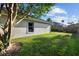 Backyard view showing the side of the house, green grass, and palm trees at 10516 Gretna Green Dr, Tampa, FL 33626