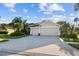 Traditional home featuring a manicured lawn, lush tropical plants, and a spacious three-car garage at 10516 Gretna Green Dr, Tampa, FL 33626