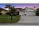 Traditional home featuring a manicured lawn, lush tropical plants, and a spacious three-car garage at 10516 Gretna Green Dr, Tampa, FL 33626