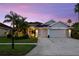Charming home with a well-manicured lawn, tropical plants, and a two-car garage during dusk at 10516 Gretna Green Dr, Tampa, FL 33626