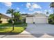 Traditional home featuring a manicured lawn, lush tropical plants, and a spacious three-car garage at 10516 Gretna Green Dr, Tampa, FL 33626