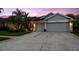 Home featuring a 3-car garage and lush landscaping with concrete driveway at dusk at 10516 Gretna Green Dr, Tampa, FL 33626