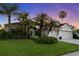 Charming home boasts lush landscaping, vibrant green lawn, and stately palm trees at dusk at 10516 Gretna Green Dr, Tampa, FL 33626