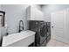 Laundry room with gray washer and dryer, white cabinets, utility sink, and neutral-toned tile flooring at 10516 Gretna Green Dr, Tampa, FL 33626