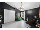 Study featuring dark walls, a unique chandelier, a comfortable green loveseat, and bright white trim at 10516 Gretna Green Dr, Tampa, FL 33626