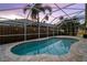 Screened-in pool featuring a unique shape surrounded by light-colored stone pavers with a view of the fenced yard at 10516 Gretna Green Dr, Tampa, FL 33626