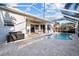 A beautiful enclosed pool with a spacious stone patio and an outdoor dining area under a ceiling fan at 10516 Gretna Green Dr, Tampa, FL 33626