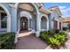 Arched entrance to a blue home, showcasing the brick walkway and manicured landscaping around the front door at 10645 Ruffino Ct, Trinity, FL 34655