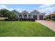 Charming blue home features a well-manicured lawn, lush landscaping, and a brick driveway leading to a two-car garage at 10645 Ruffino Ct, Trinity, FL 34655