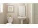Neutral bathroom features a modern pedestal sink, toilet, decorative mirror, and ample space at 11083 E 65Th Ter, Palmetto, FL 34221
