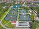 Aerial view featuring multiple tennis courts, shuffleboard courts, and surrounding community amenities at 1110 Jasmine Creek Ct, Sun City Center, FL 33573
