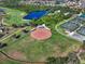 Aerial view of baseball field with backstop and recreation areas, adjacent to a pond and surrounding neighborhood at 1110 Jasmine Creek Ct, Sun City Center, FL 33573