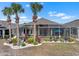 Exterior back of home featuring lanai with patio furniture, landscaping, and palm trees at 1110 Jasmine Creek Ct, Sun City Center, FL 33573