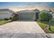A charming home featuring a well-maintained lawn, brick driveway, and a two-car garage under a sunset sky at 1110 Jasmine Creek Ct, Sun City Center, FL 33573