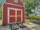 Charming red storage shed with double doors, providing ample storage space for outdoor equipment and tools at 11912 Mcmullen Loop, Riverview, FL 33569