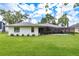 Back exterior view with a screened-in lanai and a well-manicured lawn at 120 Fernbrook Rd, Oldsmar, FL 34677