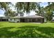 Rear view of a well-maintained home with a spacious screened-in patio and green lawn at 120 Fernbrook Rd, Oldsmar, FL 34677