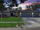 Charming single-story home with a well-maintained lawn and mature trees, plus a three car garage and colorful sunset at 120 Fernbrook Rd, Oldsmar, FL 34677