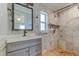 Bathroom featuring white marble tiled walls, single sink vanity, and shower at 1242 Bermuda St, Clearwater, FL 33755