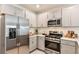 Modern kitchen featuring stainless steel appliances, gray cabinets, and a stylish design at 12435 Gust Ct, Hudson, FL 34669