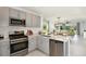 Well-lit kitchen showcases stainless appliances, gray cabinets, and open layout to the dining area at 12435 Gust Ct, Hudson, FL 34669