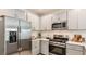 Modern kitchen with stainless steel appliances, light grey cabinets, and quartz countertops at 12469 Gust Ct, Hudson, FL 34669