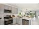 Bright kitchen with stainless steel appliances and gray cabinets flowing into the living room in an open concept design at 12469 Gust Ct, Hudson, FL 34669