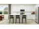 A bright kitchen with white cabinetry, stainless steel appliances, and a central island with bar seating at 12597 Lily Quartz Loop, Parrish, FL 34219