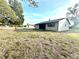 Large grassy backyard with a view of exterior white siding and screened patio at 13100 Serpentine Dr, Hudson, FL 34667