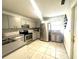 Bright kitchen with stainless steel appliances, grey cabinets, tiled backsplash, and neutral tile flooring at 13100 Serpentine Dr, Hudson, FL 34667