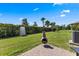 Landscaped backyard featuring a chiminea on brick pavers, grassy area, and a fenced perimeter with palm trees at 1321 Custer Bayou St, Ruskin, FL 33570