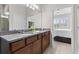 Bathroom featuring double vanity with granite countertops and an ensuite bedroom with white plantation shutters at 1321 Custer Bayou St, Ruskin, FL 33570