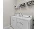 Laundry room with stacked washer and dryer, wire shelf, white walls, and grey floor mat at 1321 Custer Bayou St, Ruskin, FL 33570
