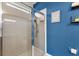 Shower with glass enclosure and blue accent wall with decorative shelves and a decorative sign at 1321 Custer Bayou St, Ruskin, FL 33570