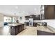 Modern kitchen with granite countertops, a stainless steel refrigerator, and dark cabinetry at 13903 Sage Thrasher Ln, Riverview, FL 33579