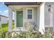 Cozy front porch with a green door, complemented by a small bench and lush landscaping at 13958 Richland Gulf Cir, Parrish, FL 34219
