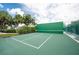 An empty green racquetball court with white lines is surrounded by lush greenery and a fence, ready for a game at 14840 Shipwatch Trce # 1924, Largo, FL 33774