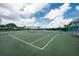An empty green tennis court is ready for play on a sunny day with blue skies and fluffy white clouds above at 14840 Shipwatch Trce # 1924, Largo, FL 33774