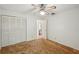A bright bedroom features a ceiling fan, neutral walls, double closet doors, and wall to wall carpeting at 1521 Fireside St, Port Charlotte, FL 33952