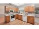 Charming kitchen with wood cabinets, white appliances, and a mosaic backsplash, offering a cozy cooking space at 1521 Fireside St, Port Charlotte, FL 33952