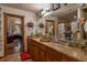 Dual-sink bathroom with stone countertops, large mirror, and decoratively draped doorway at 15625 Olney Ln, Spring Hill, FL 34610