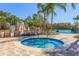 Community pool and hot tub with splash pad and seating, surrounded by lush landscaping and palms at 20403 Sultana Ct, Tampa, FL 33647