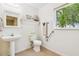 Bright bathroom with a pedestal sink, toilet, and a window view of lush greenery at 2205 Henley Rd, Lutz, FL 33558